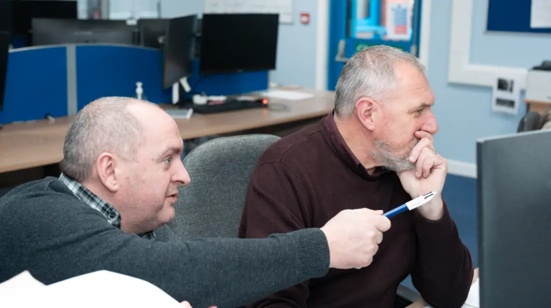 Two Jenkar team members reviewing work at a monitor